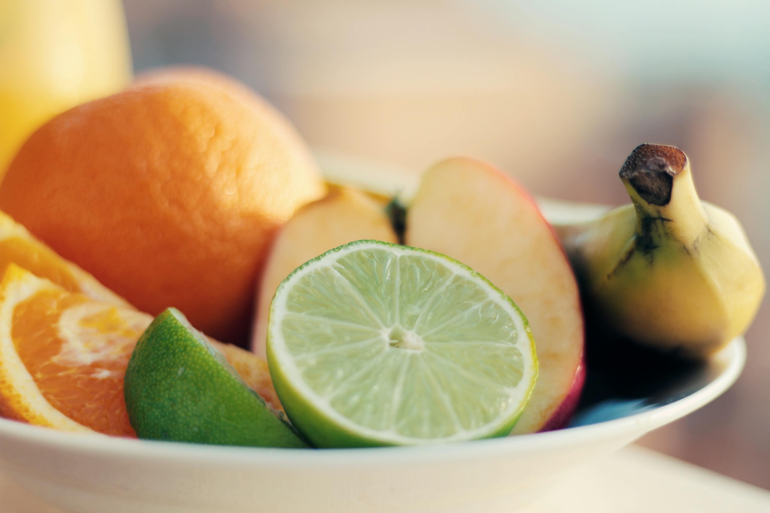 A close-up of a fresh mixed fruit bowl featuring citrus, banana, and apple slices for a healthy snack.