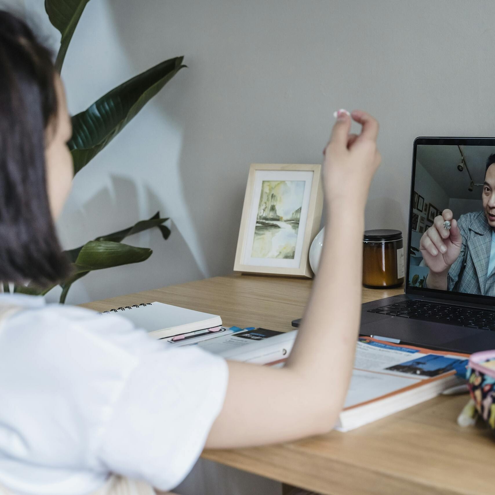 Child attends an online class with a teacher via video call on a laptop.