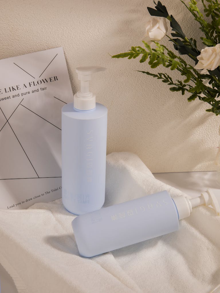 Minimalist shot of luxury dispenser bottles with botanical decor and copyspace.